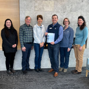 Staff and two donors stand together for a picture, the excutive director holds a check.