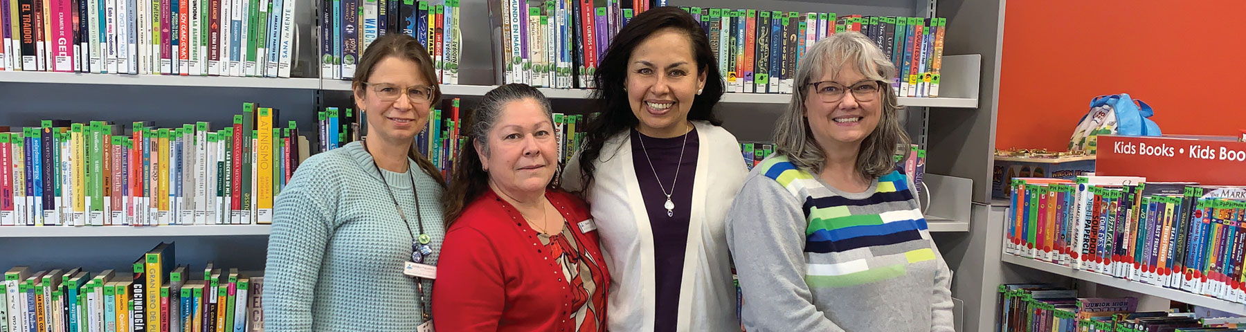 Staff who work at the Branch smile together in front of an assortment of books at the Branch.